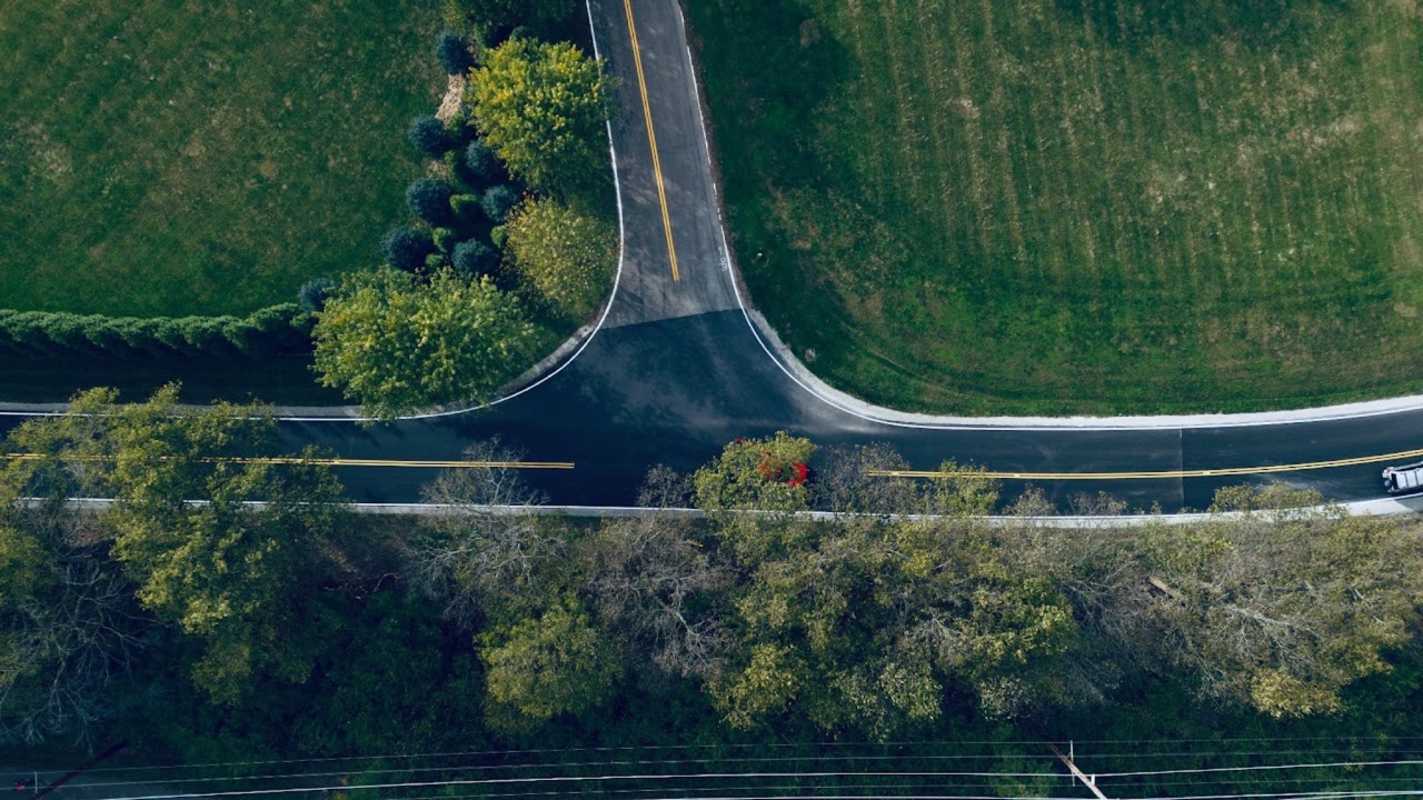 Top-down view of a road intersection between green fields
