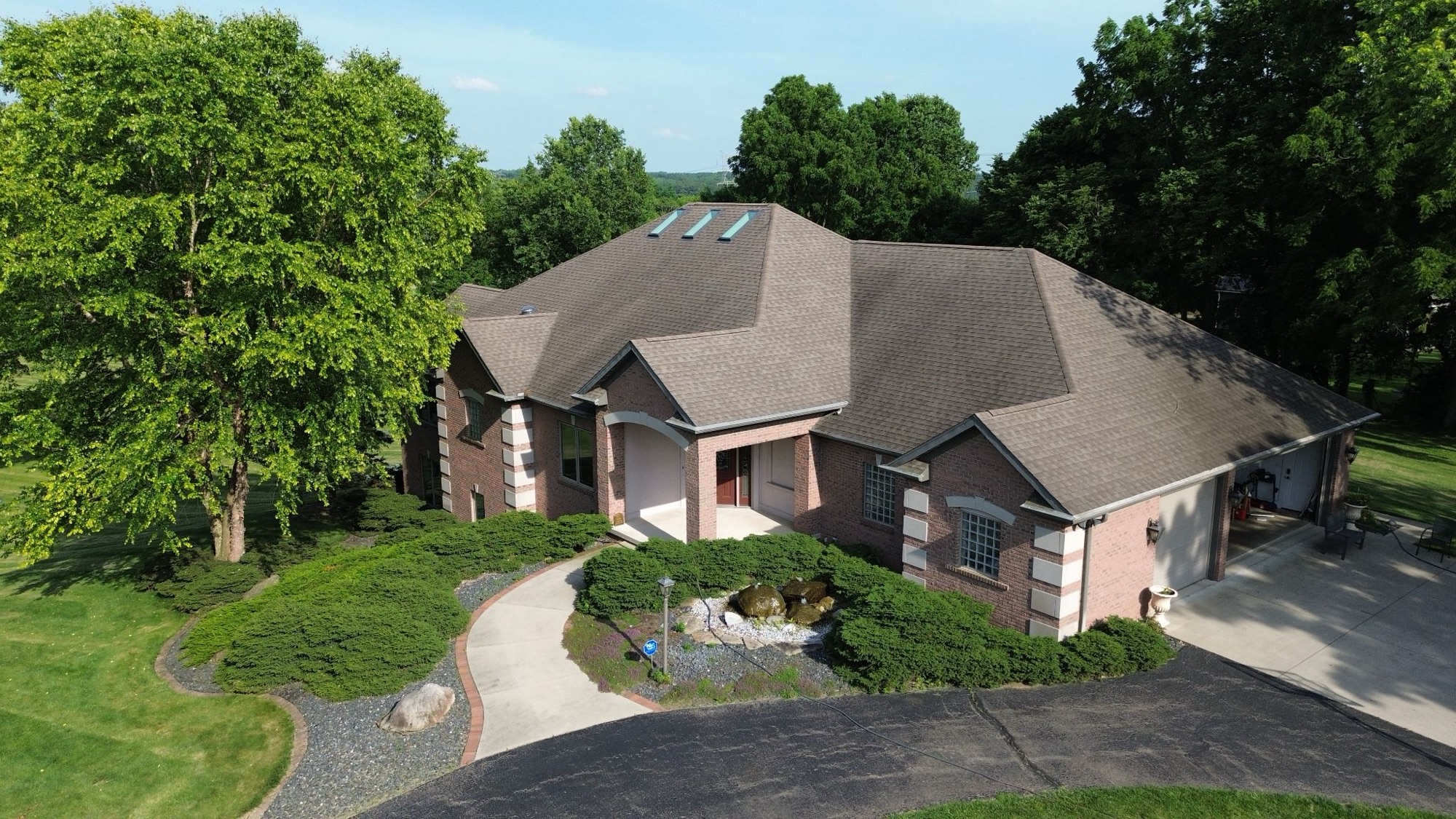 Aerial view of a brick home with a circular driveway surrounded by mature trees